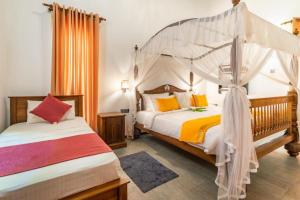 a bedroom with two beds and a canopy bed at Alai Resort in Mullaittivu +27 photos
