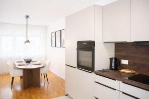 a kitchen with white cabinets and a small table with chairs at Ferienwohnung Südwind 3 in Küssaberg