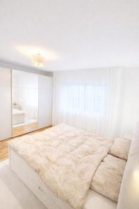 a white bedroom with a large bed and a sink at Ferienwohnung Südwind 3 in Küssaberg