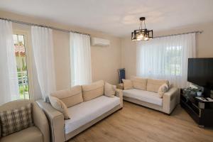 a living room with two couches and a flat screen tv at Villa Kumsal in Kuşadası