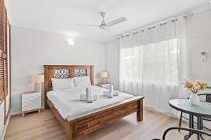 a white bedroom with a large bed and a table at Capricorn Whitsunday in Cannonvale