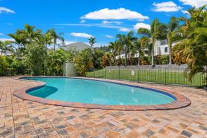 a swimming pool in a yard with palm trees at Capricorn Whitsunday in Cannonvale