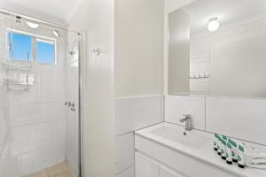 a white bathroom with a sink and a shower at Capricorn Whitsunday in Cannonvale +2 photos