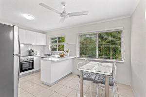 a white kitchen with a table and a ceiling fan at Capricorn Whitsunday in Cannonvale