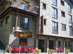 Un bâtiment avec un groupe de chaises rouges devant lui dans l'établissement Apartaments Bonet, à Pal