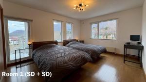 two beds in a room with windows at Ts House Hakodate Park Front in Hakodate