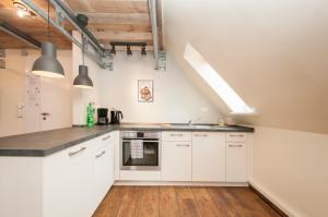 cocina con armarios blancos y suelo de madera en Appartement "7up" contacless Check in, en Hamburgo