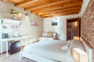 una camera con un letto bianco e un muro di mattoni di La Piccola Matilde a Desenzano del Garda
