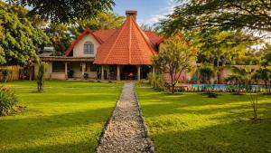 a house with an orange roof on a green lawn at Kitunduni Lodge in Arusha