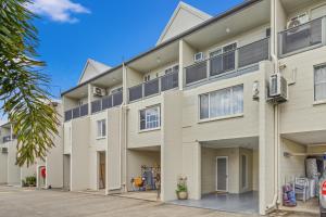 an exterior view of a large white building with windows at Capricorn Whitsunday in Cannonvale