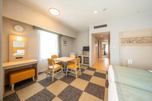 a hotel room with a bed and a table and chairs at Hotel Monterey La Soeur Naha in Naha