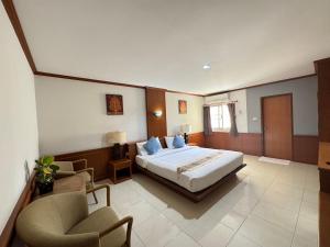 a bedroom with a bed and two chairs at โรงแรมสยามบูทีค บุรีรัมย์ in Buriram +26 photos
