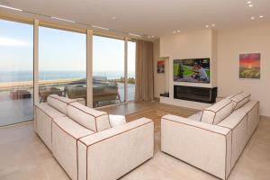 a living room with two white chairs and a tv at Luxury Pool Villa Palasea With Panoramic Sea View in Vlorë