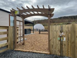 a wooden pergola next to a wooden fence at Maneight Retreat with Hot tub in New Cumnock