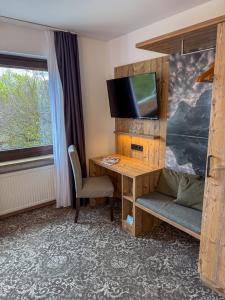 a room with a desk with a tv and a bed at Hotel-Restaurant Dechbettener Hof in Regensburg