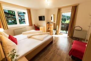 1 dormitorio con 1 cama blanca grande y ventanas en "Quality Hosts Arlberg" Hotel-Gasthof Freisleben en Sankt Anton am Arlberg