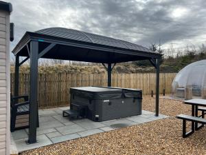 a black gazebo with a grill on a patio at Maneight Retreat with Hot tub in New Cumnock