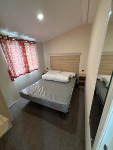 a small bedroom with a bed and two windows at Seaside Lodge Haven in St Osyth in Jaywick Sands +61 photos