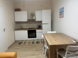 a kitchen with a wooden table and white cabinets at Casa Vacanze Nicol in Licata +3 photos