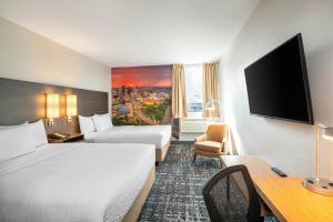 a hotel room with two beds and a flat screen tv at Clarion Pointe in Winnipeg