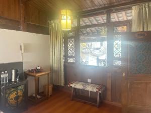 a room with a window and a bench next to a door at Baisha Holiday Resort Lijiang in Lijiang
