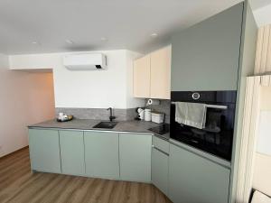 a kitchen with white cabinets and black appliances at Breeze Studio in Palanga +13 photos