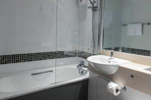 a bathroom with a sink and a bath tub with a mirror at Newton Park Country House Hotel in Burton upon Trent