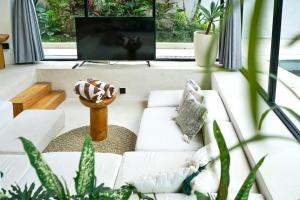 a living room with a couch and a tv at Dzen Greenfield Villa 6 in Ubud