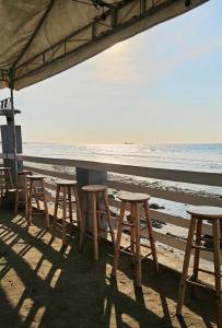 a row of tables and stools on the beach at Charlie's Hangar Surf Hostel in San Juan