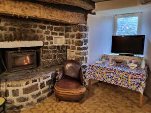 a living room with a stone fireplace and a chair at Maison ferme équestre du Ténéré in Saint-Jean-Lachalm