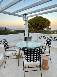 a glass table and chairs on a patio at Corfu Olive Village with Swimming Pool Castello Di Vista in Análipsis