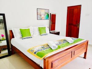 a bedroom with a large white bed with green pillows at Sampath Grand Hotel in Mawanella