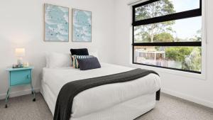 a white bedroom with a bed and a window at Fleetwood Atelier in Frankston South