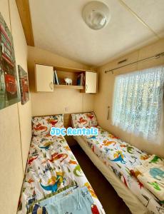 a small bedroom with two beds and a window at Palins - KC19 in Kinmel Bay