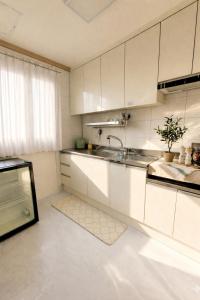 a kitchen with white cabinets and a sink at 전주한옥마을 스테이네슬 in Jeonju
