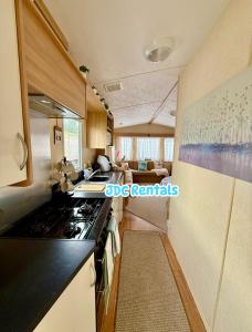 a kitchen with a stove top oven next to a living room at Palins - KC19 in Kinmel Bay