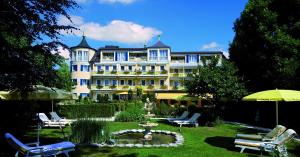 a large building with a yard with chairs and a fountain at Hotel & Spa Fontenay in Bad Wörishofen