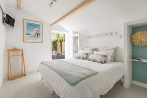 a white bedroom with a large white bed with pillows at Escale et bien-être in Pornic