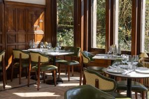 a restaurant with tables and chairs and windows at Newton Park Country House Hotel in Burton upon Trent
