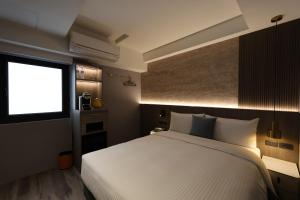 a bedroom with a white bed and a window at Fun Stay Inn Hanzhong in Taipei