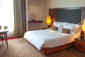a hotel room with a large bed and a desk at The Heritage Grand Khon Kaen Hotel and Convention in Khon Kaen