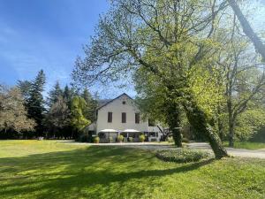 a white house with a tree in a field at La Source in Saint-Pierre-dʼArgençon