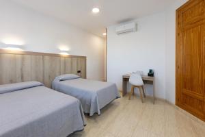 a bedroom with two beds and a desk with a chair at Hostal 82 in Olías del Rey +48 photos