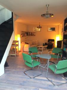 a living room with green chairs and a bedroom at Gastenverblijf Door de Poort in Tilburg
