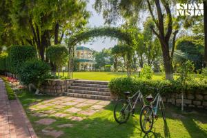 two bikes parked in the grass in front of a house at StayVista at The Hideout Farms with Lawn and private Pool in Kurukshetra