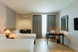 a hotel room with two beds and a desk at The Heritage Grand Khon Kaen Hotel and Convention in Khon Kaen