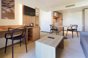 a kitchen and dining room with chairs and a table at Kyriad Prestige Residence & Spa Cabourg-Dives-sur-Mer in Dives-sur-Mer