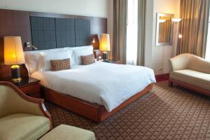 a hotel room with a large bed and two chairs at The Heritage Grand Khon Kaen Hotel and Convention in Khon Kaen