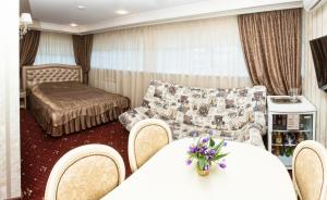sala de estar con sofá, mesa y sillas en Lazurny Bereg Hotel, en Tyumen
