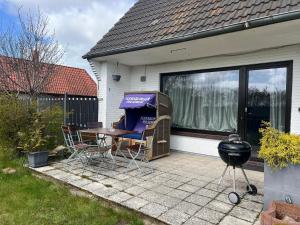 a patio with a table and chairs and a grill at Schöne Wohnung Mit Dem Garten in Jübek